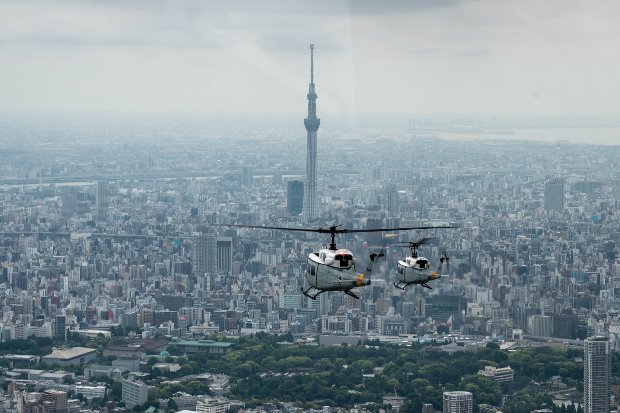 two helicopters flying over a city