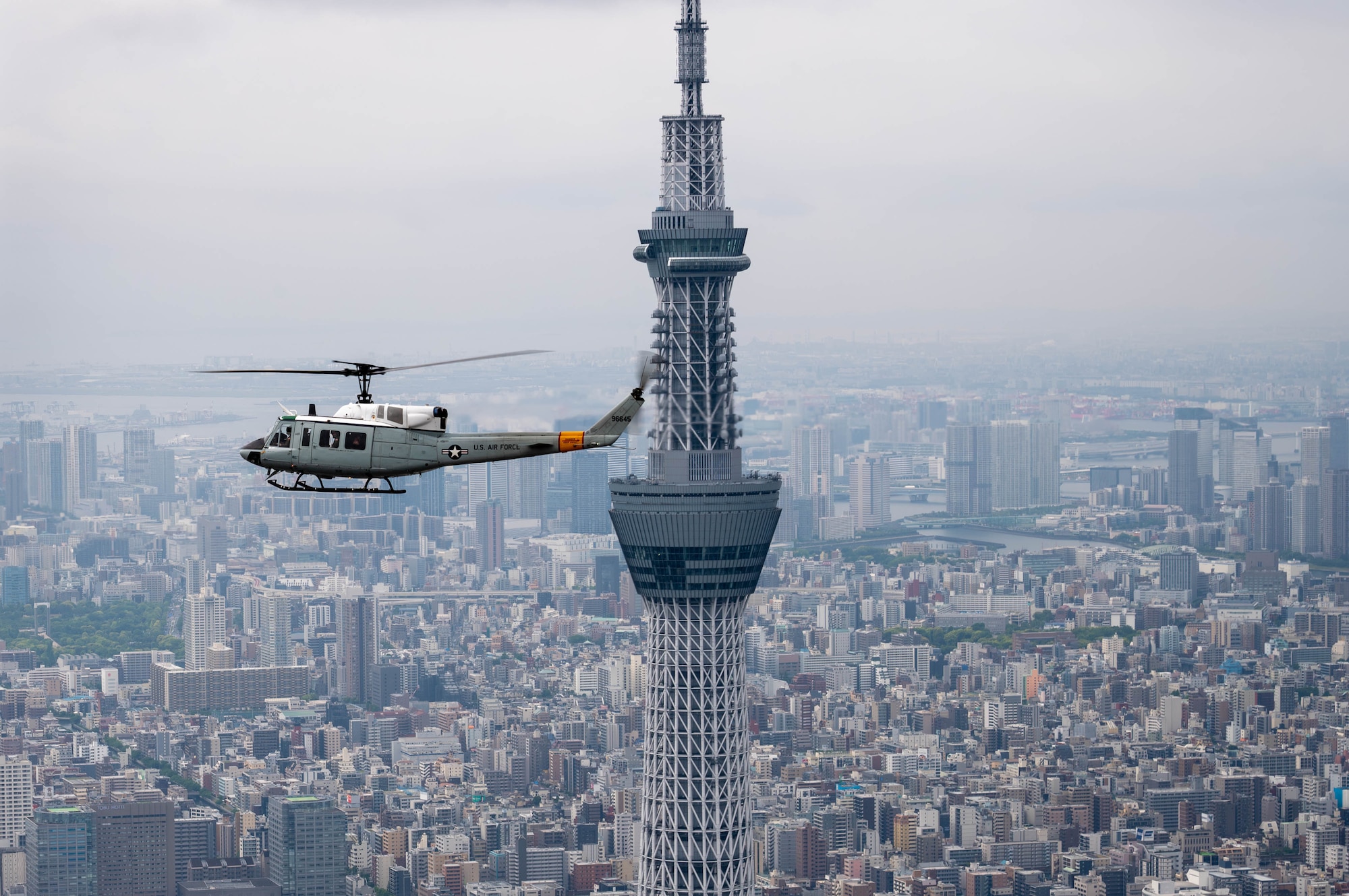 A helicopter in air near a skyscraper