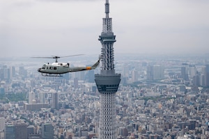 A helicopter in air near a skyscraper
