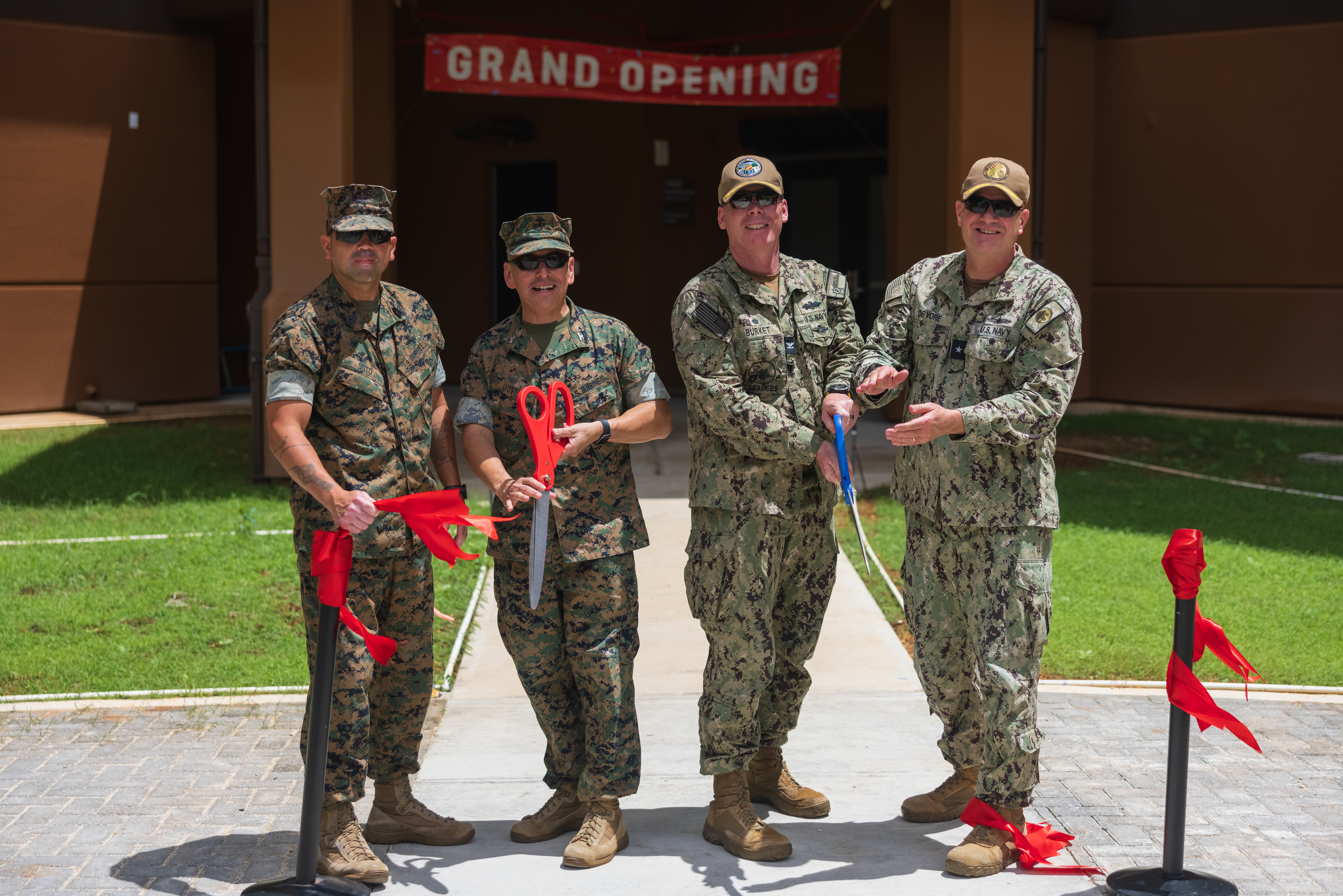 U.S. Marine Corps Base Camp Blaz senior leaders; U.S. Navy Capt. Blake Burket, commanding officer, Officer in Charge of Construction; and Rear Adm. Brent DeVore, commander, Joint Region Marianas cut a ribbon during a barracks soft opening on MCBCB, Guam, May, 16 2025. The first new enlisted barracks at MCBCB opened, marking a significant milestone in the development of the U.S. Marine Corps’ newest installation.  (Marine Corps photo by Cpl. Brayden Daniel)