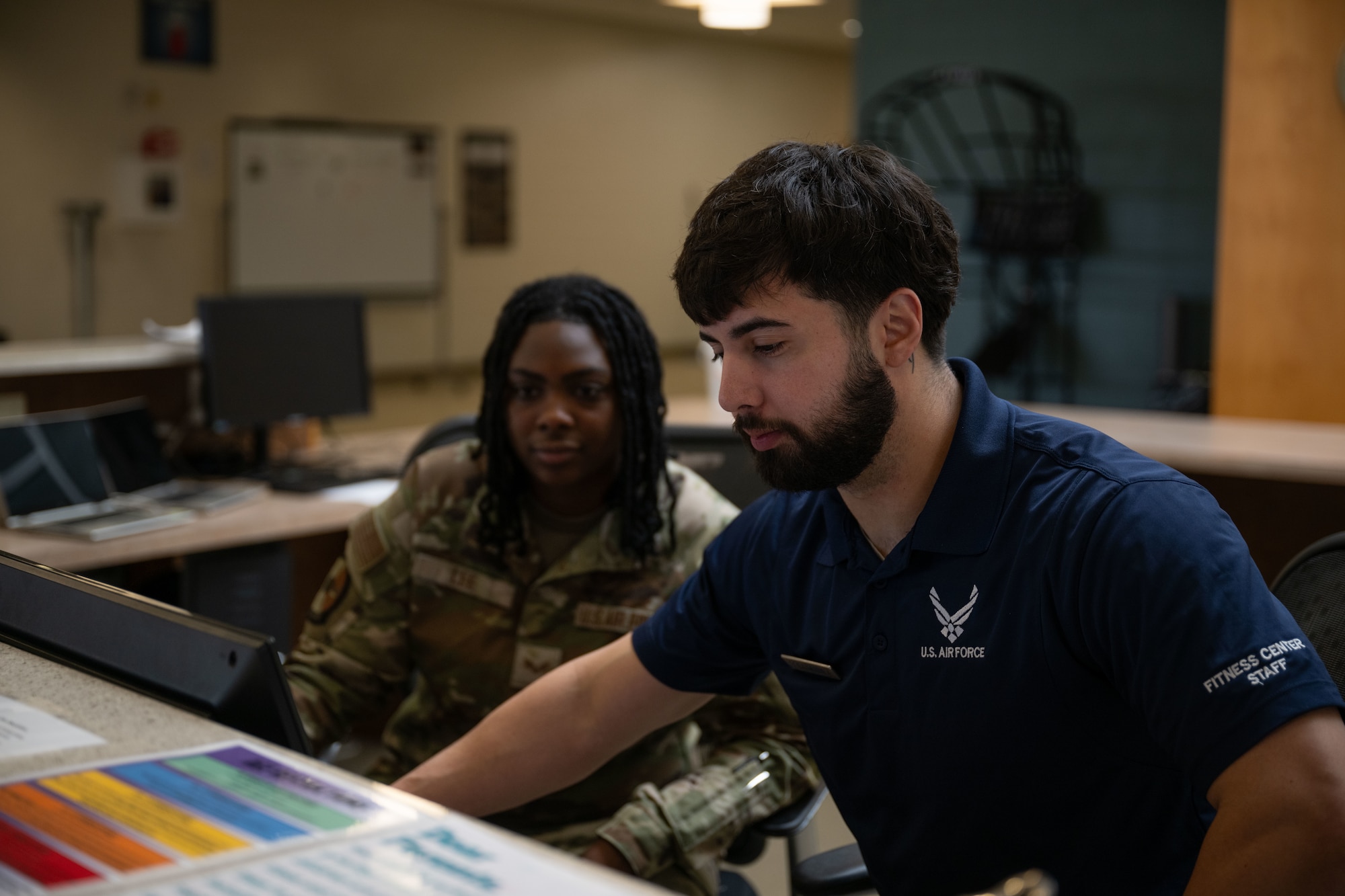 U.S. Air Force Senior Airman Jateanna Lee, left, 436th Force Support Squadron fitness specialist, and Staff Sgt. Christopher Denney, 436th FSS fitness noncommissioned officer in charge, sit at the front desk at the Fitness Center on Dover Air Force Base, Delaware, May 15, 2025. The Fitness Center offers a range of exercise equipment, classes and programs designed to improve physical fitness and overall health. (U.S. Air Force photo by Airman 1st Class Liberty Matthews)