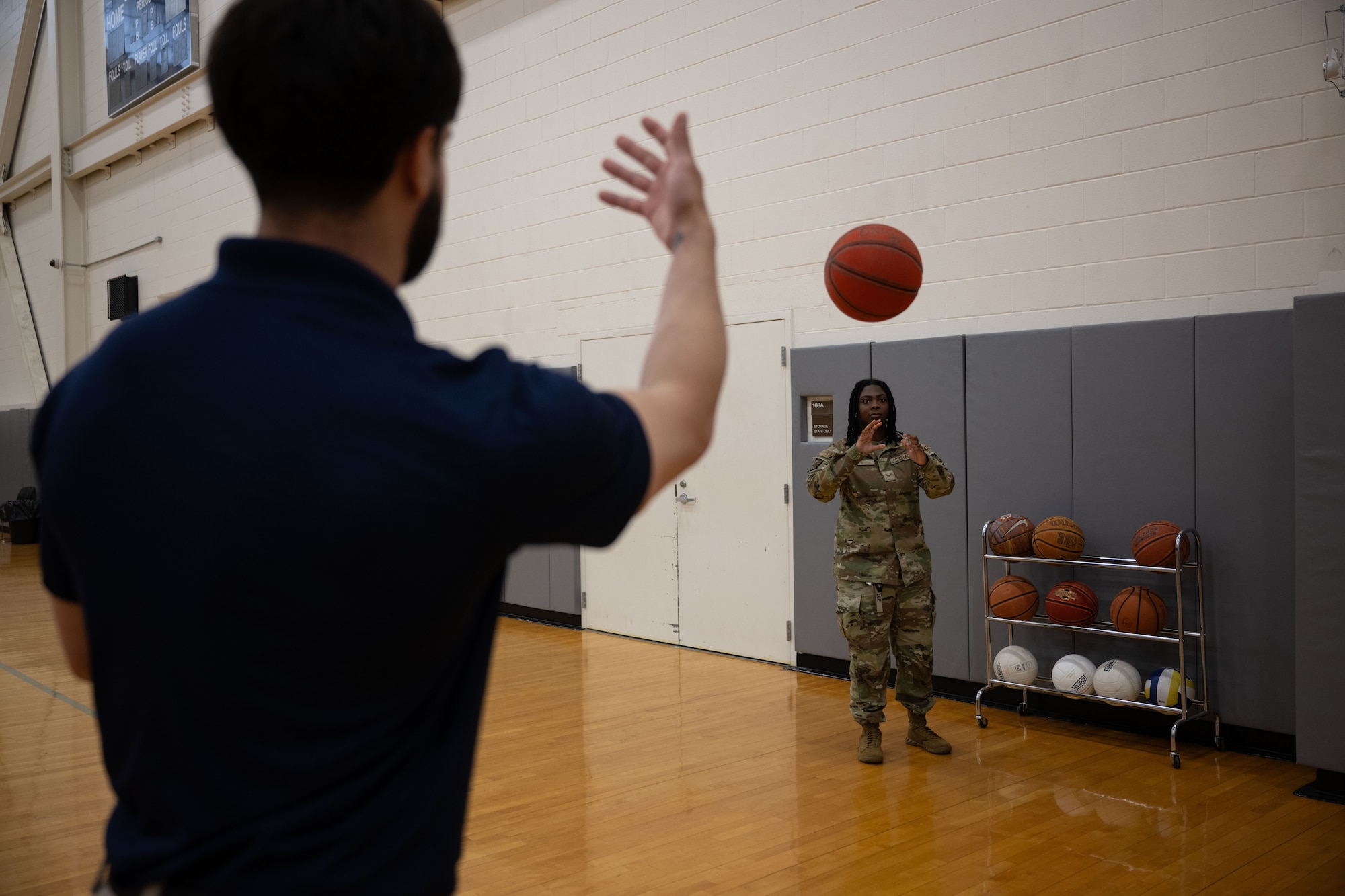 U.S. Air Force Staff Sgt. Christopher Denney, left, 436th Force Support Squadron fitness noncommissioned officer in charge, tosses a basketball to Senior Airman Jateanna Lee, 436th FSS fitness specialist, at the Fitness Center on Dover Air Force Base, Delaware, May 15, 2025. The Fitness Center offers a range of exercise equipment, classes and programs designed to improve physical fitness and overall health. (U.S. Air Force photo by Airman 1st Class Liberty Matthews)