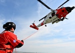 Helicopter with man on ground holding a line.
