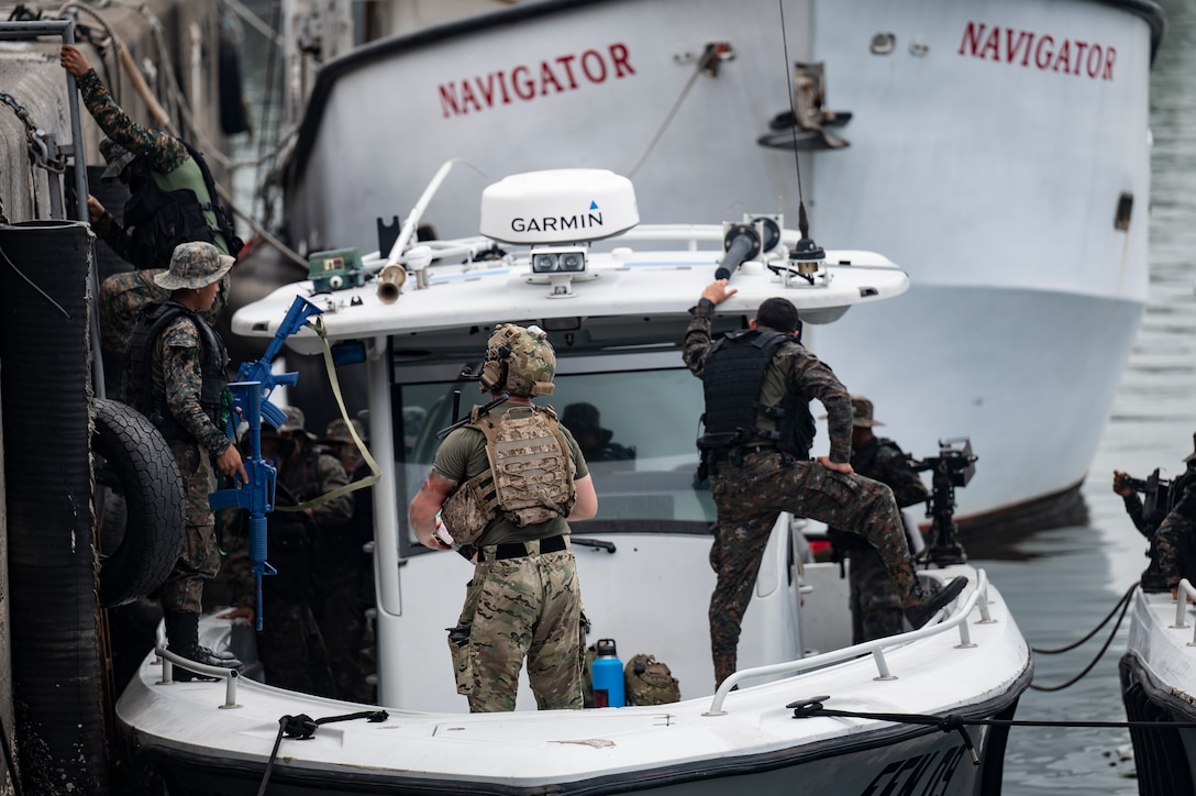 U.S. navy member stands on a boat with Guatemalan sailors