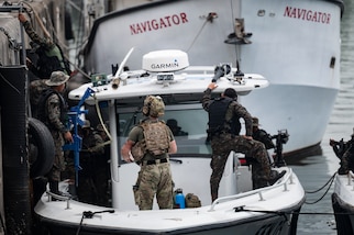 U.S. navy member stands on a boat with Guatemalan sailors