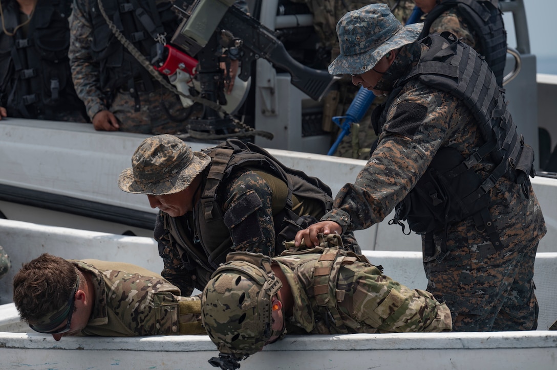 Guatemalan sailors practice a drug interdiction with two kneeling U.S. service members