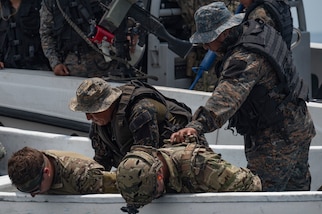 Guatemalan sailors practice a drug interdiction with two kneeling U.S. service members