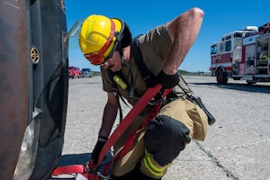 U.S. Air Force Airman 1st Class Dustin Wright, a fire protection specialist assigned to the 92nd Civil Engineer Squadron, utilizes a ratchet strap during a rescue simulation at Fairchild Air Force Base, Washington, May 6, 2025. Firefighters routinely run simulations, including controlled burns and rescue scenarios to train and prepare for the unpredictable challenges of real-life emergencies, ensuring they can react effectively and safely under pressure. (U.S. Air Force photo by Airman 1st Class Samantha Thorn).