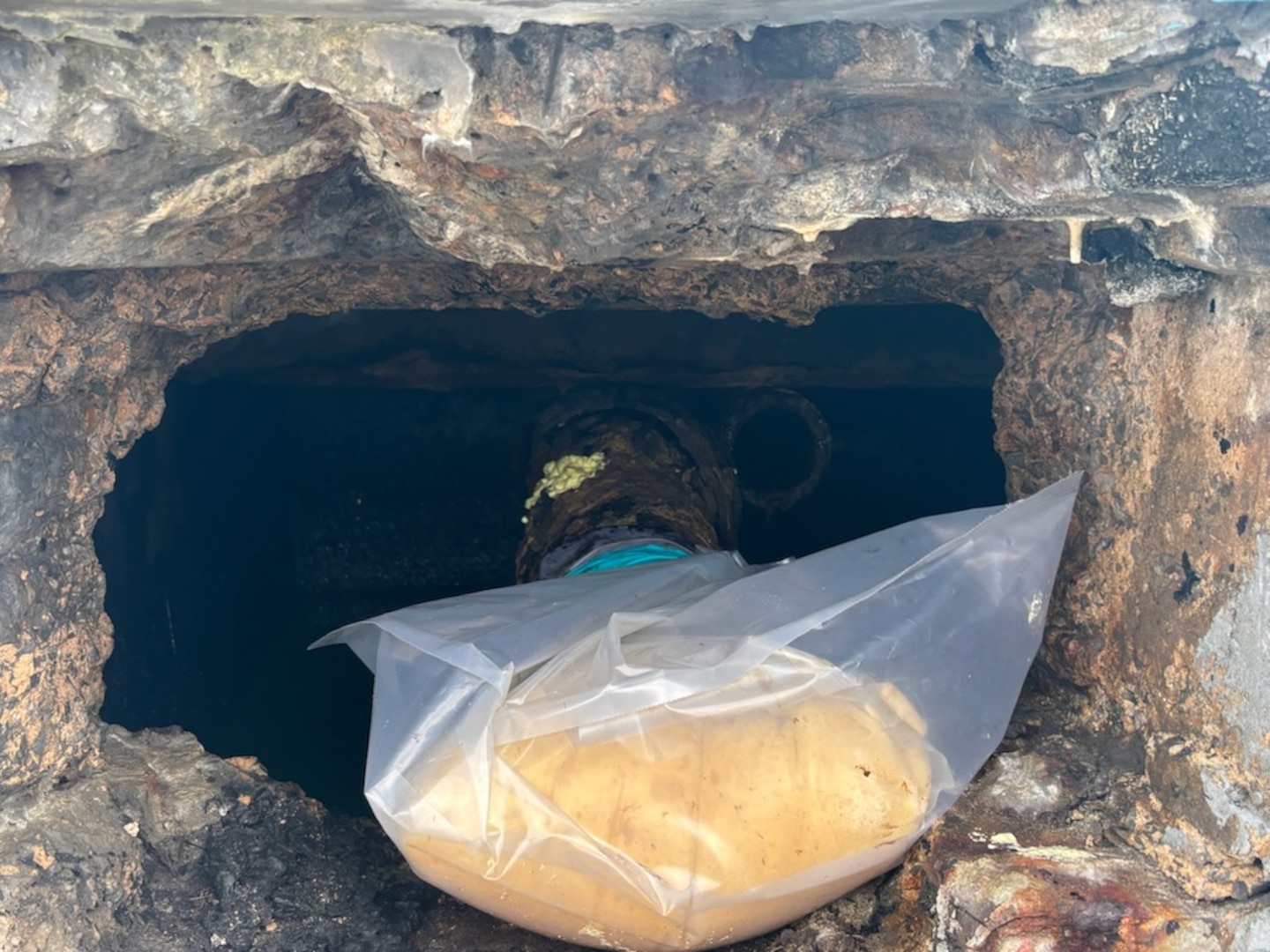 Photo of legacy pipe discharging oil, wrapped in plastic and absorbent boom, between Piers 2 and 3 in San Juan Harbor, Puerto Rico.  Coast Guard. Since April 11, 2025, Coast Guard Sector San Juan’s Incident Management team is investigating, responding and working with contracted oil spill removal organizations and local government authorities to contain and mitigate the pollution threat and clean up any recoverable product.  (U.S. Coast Guard photo)