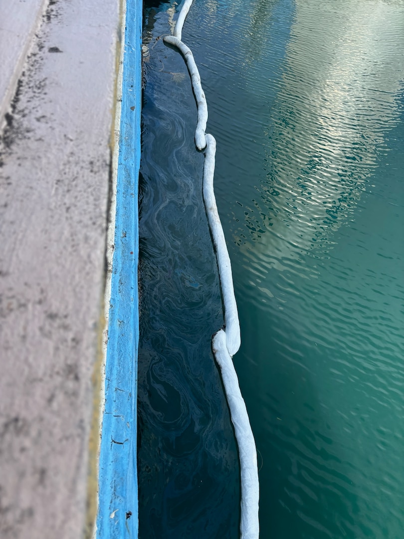 Photo showing absorbent booms deployed in clean-up site for a legacy pipe discharging oil between Piers 2 and 3 in San Juan Harbor, Puerto Rico. Since April 11, 2025, Coast Guard Sector San Juan’s Incident Management team is investigating, responding and working with contracted oil spill removal organizations and local government authorities to contain and mitigate the pollution threat and clean up any recoverable product.  (U.S. Coast Guard photo)