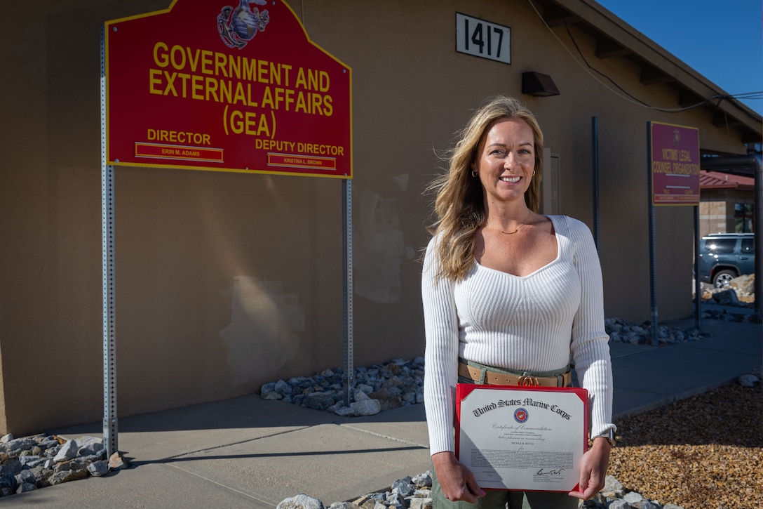 Nicole Hitch, a Missouri native, community liaison with G-7, Government and External Affairs, Marine Air Ground Task Force Training Command, Marine Corps Air Ground Combat Center, poses for a photo with her 2024 Training and Education Command Junior Civilian of the Year certificate at MCAGCC, Twentynine Palms, California, May 14, 2025. Nicole was recognized for her outstanding contributions in building strategic relationships and liaison support. She developed and maintained a dynamic and far-reaching liaison network spanning federal, state, regional, and local government levels. (U.S. Marine Corps photo by Sgt. Makayla Elizalde)