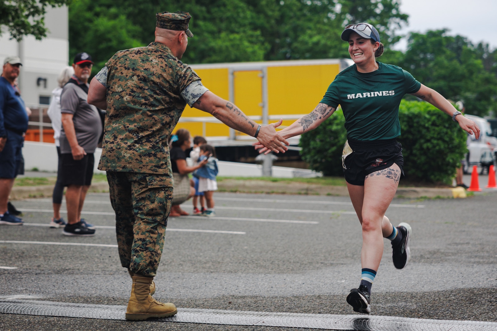 U.S. Marine Corps Sgt. Maj. Michael Brown, sergeant major of Marine Corps Base Quantico, left, high fives Anna Rubino, a native of Pennsylvania, while she crosses the finish line at the 2025 Semper Fred 5K race in Fredericksburg, Virginia, May 17, 2025. The Semper Fred 5k is a family-friendly, all ages event in historic Fredericksburg, the day before the Marine Corps Historic Half. (U.S. Marine Corps photo by Lance Cpl. Braydon Rogers)