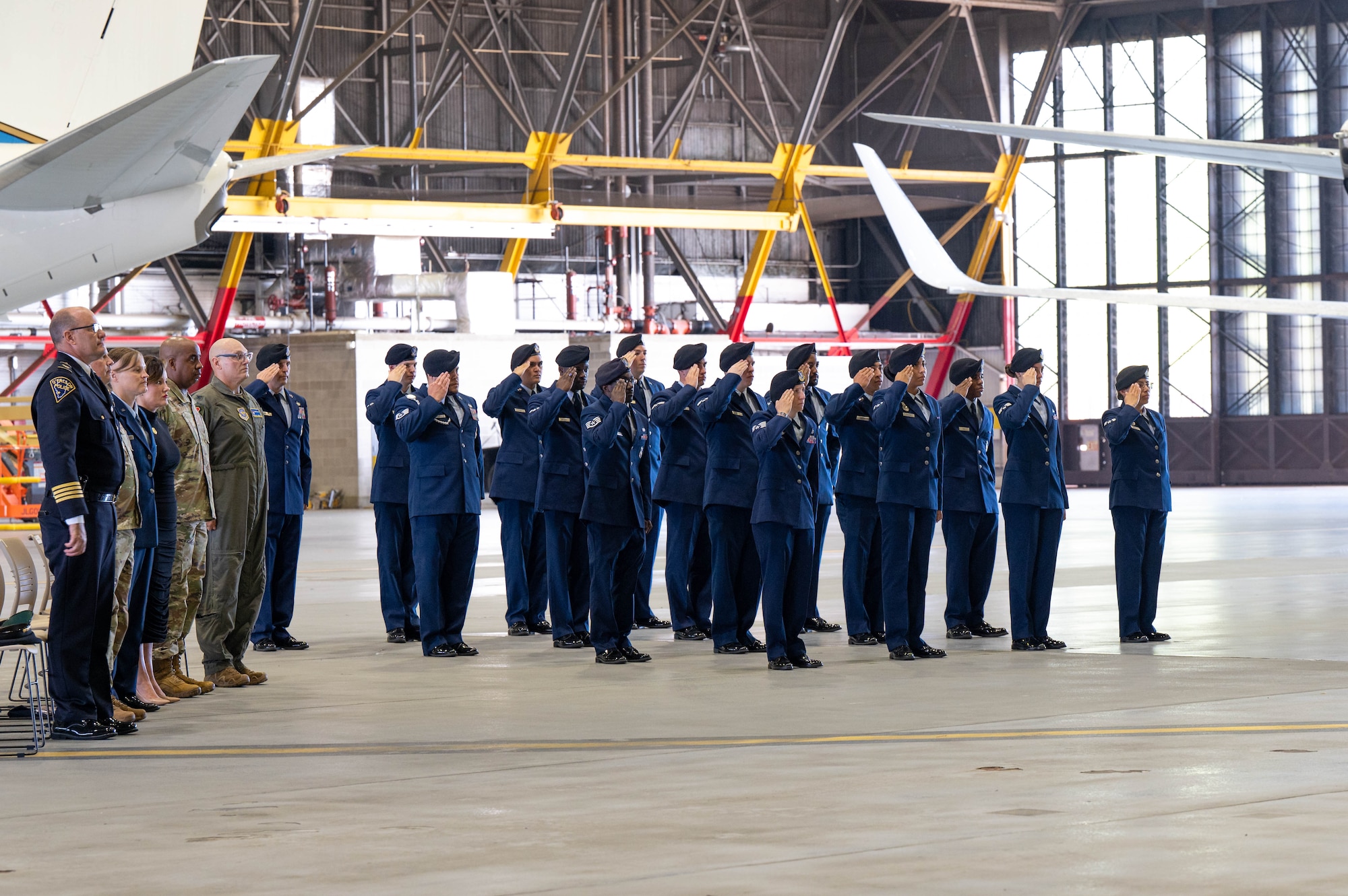 Airmen assigned to the security forces squadron render a salute while in formation wearing blues as the honor guardsmen performed the Three Volley Salute and TAPS.