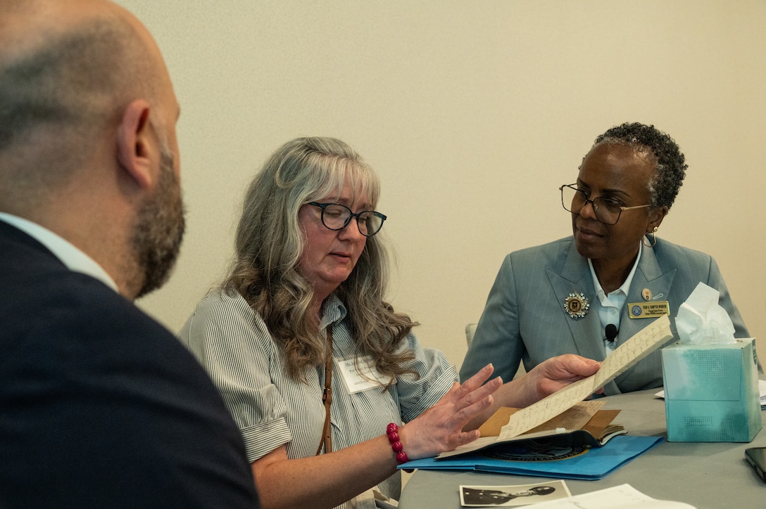 Dr. Kyle Bracken, research branch chief in the Indo Pacific Directorate of the Defense POW/MIA Accounting Agency, Jennifer McDaniel, family member of a missing in action service member, and Fern Sumpter Winbush, principal deputy director of DPAA, view the last letter McDaniel’s great uncle sent before his disappearance in World War II during a Family Member Update in Bellevue, Washington, May 3, 2025.