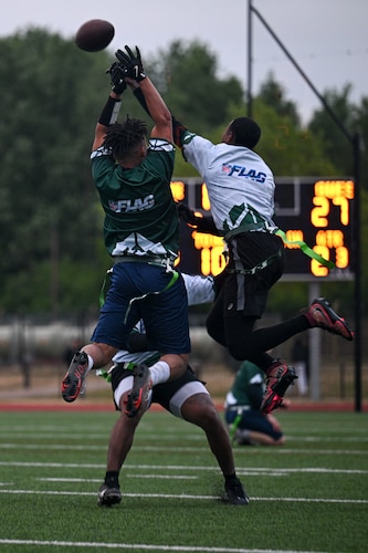 Two players jump and reach for a football during an American football game