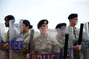 Military police officers stand in a riot control formation