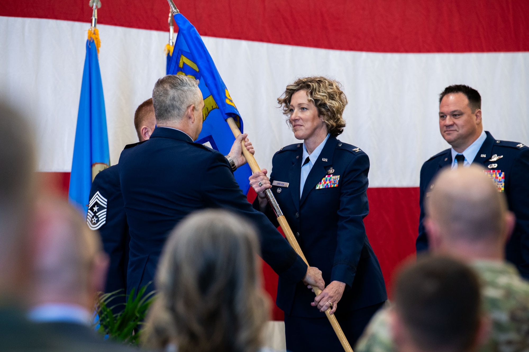 An uniformed woman receives a guidon from another uniformed member.