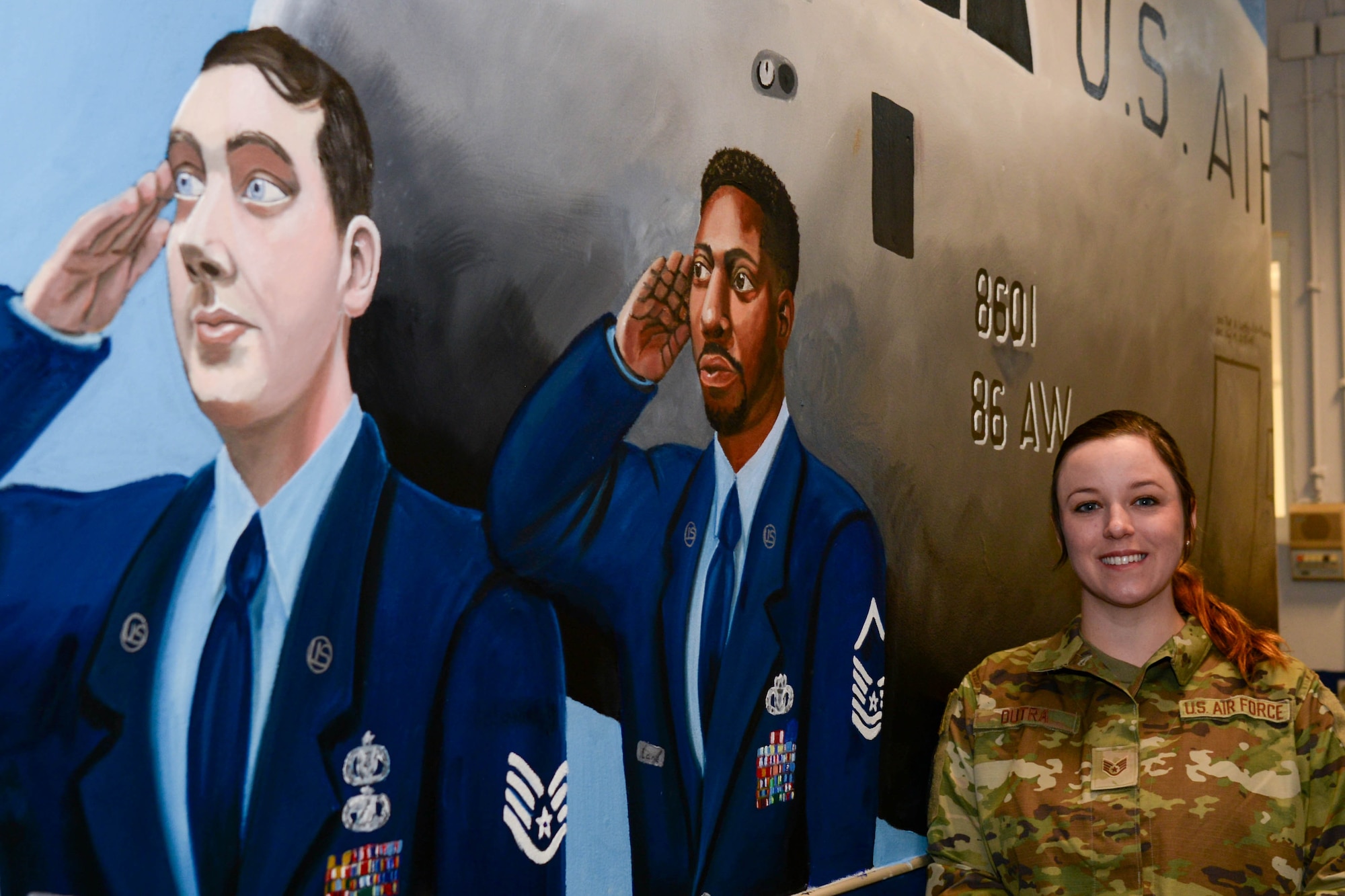Staff Sgt. Amber Dutra poses next to mural she painted.