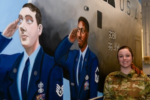 Staff Sgt. Amber Dutra poses next to mural she painted.