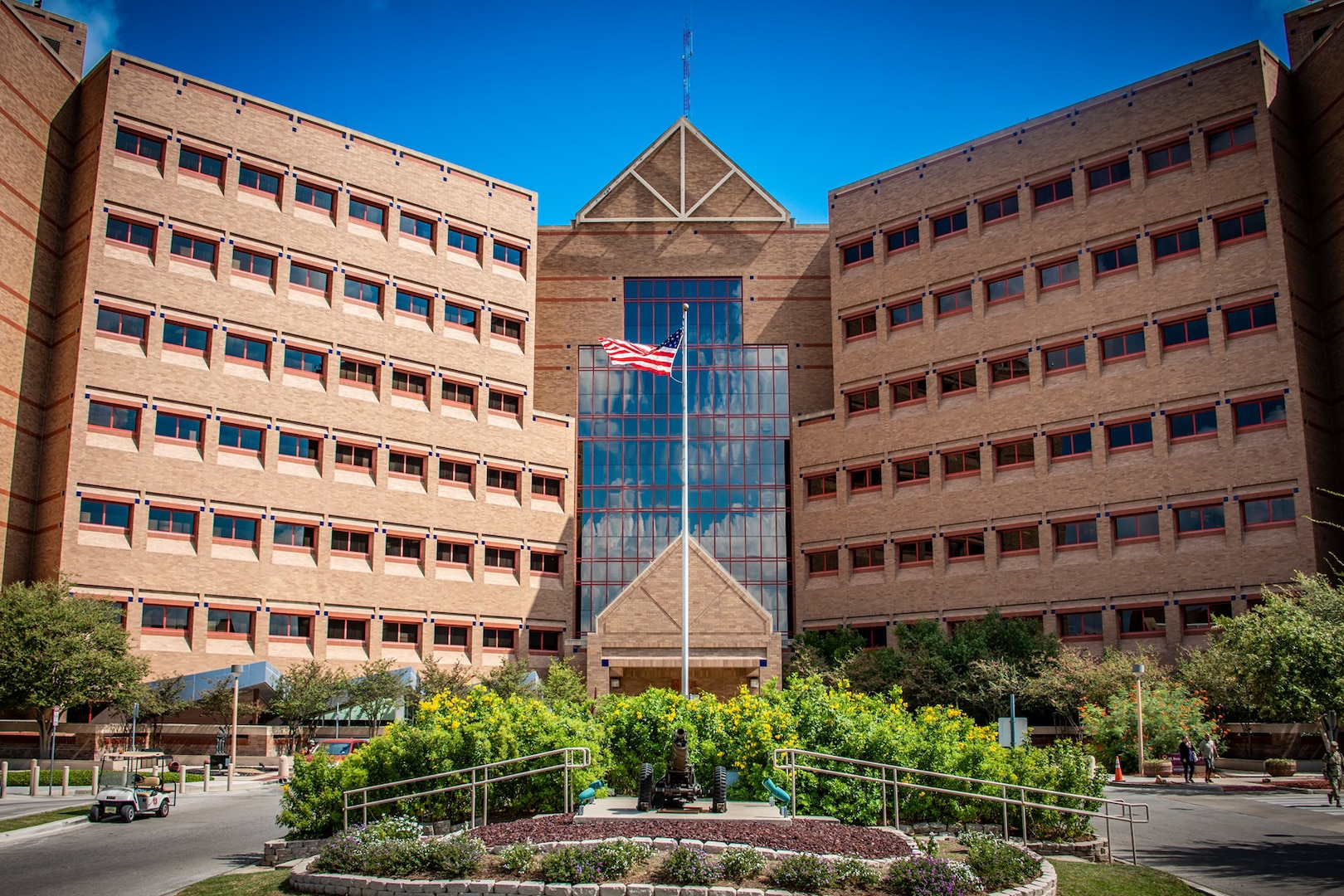 An American flag waves in front of a brown building.