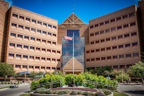 An American flag waves in front of a brown building.