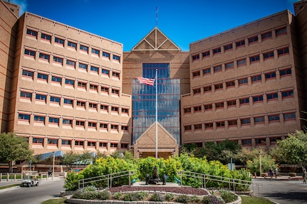 An American flag waves in front of a brown building.