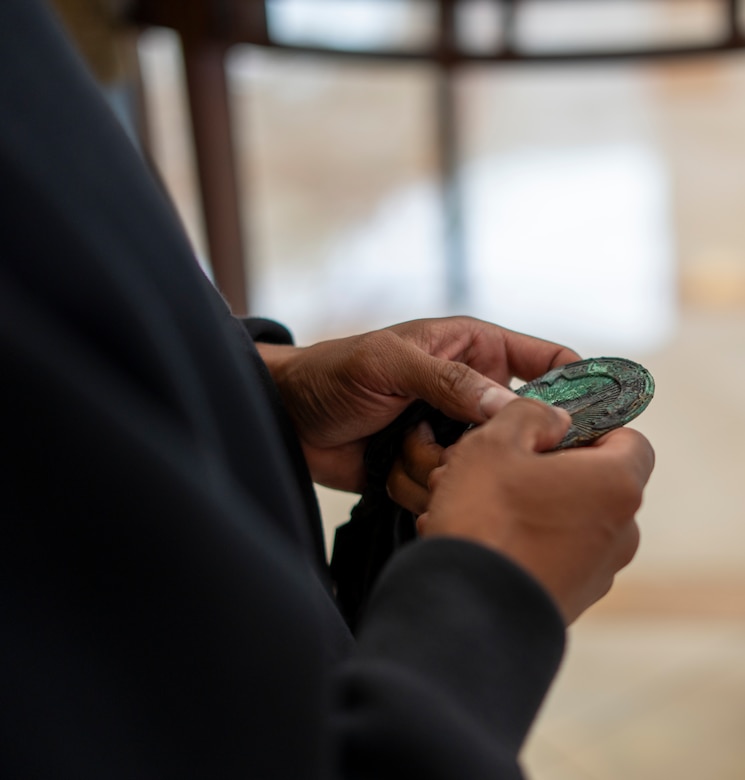 A charred but intact police badge belonging to Derek Russell Jr.’s late father rests in Russell’s hand May 5 at the Southern California Wildfire Recovery Field Office building lobby in Pasadena, California, after being recovered by a U.S. Army Corps of Engineers contractor from the remains of Russell’s home.
