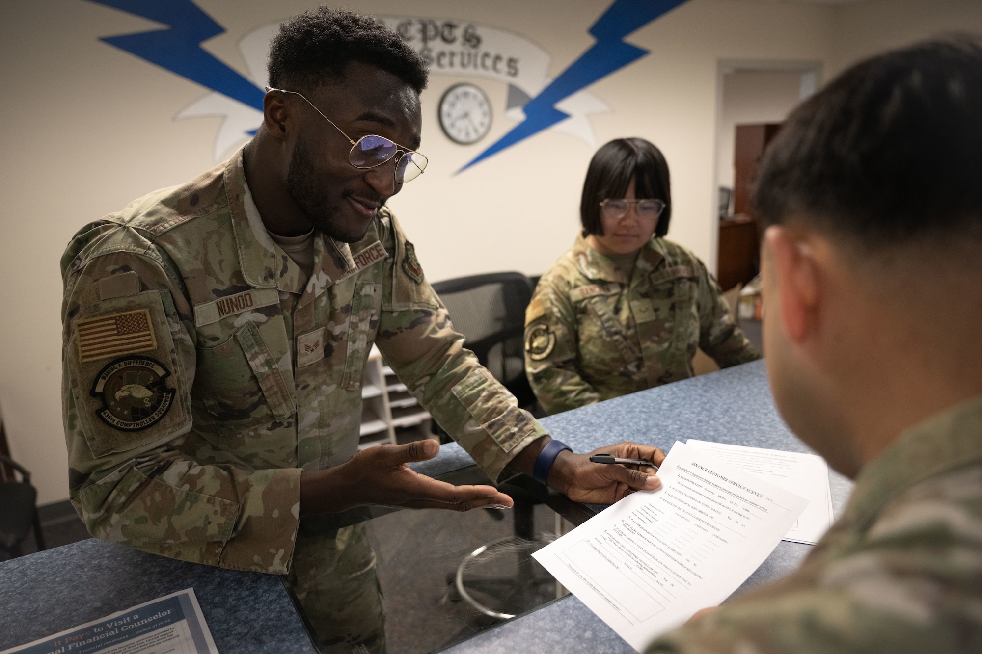 U.S. Air Force Senior Airman Kobina Nunoo, left, 436th Comptroller Squadron financial operation technician, interacts with a customer at Dover Air Force Base, Delaware, April 29, 2025. The 436th CPTS is responsible for funds accounting and budget planning, programming, execution and analysis. The squadron also supports Air Mobility Command worldwide mobility requirements through funds disbursement, travel order processing and deployment of personnel. (U.S. Air Force photo by Airman 1st Class Liberty Matthews)