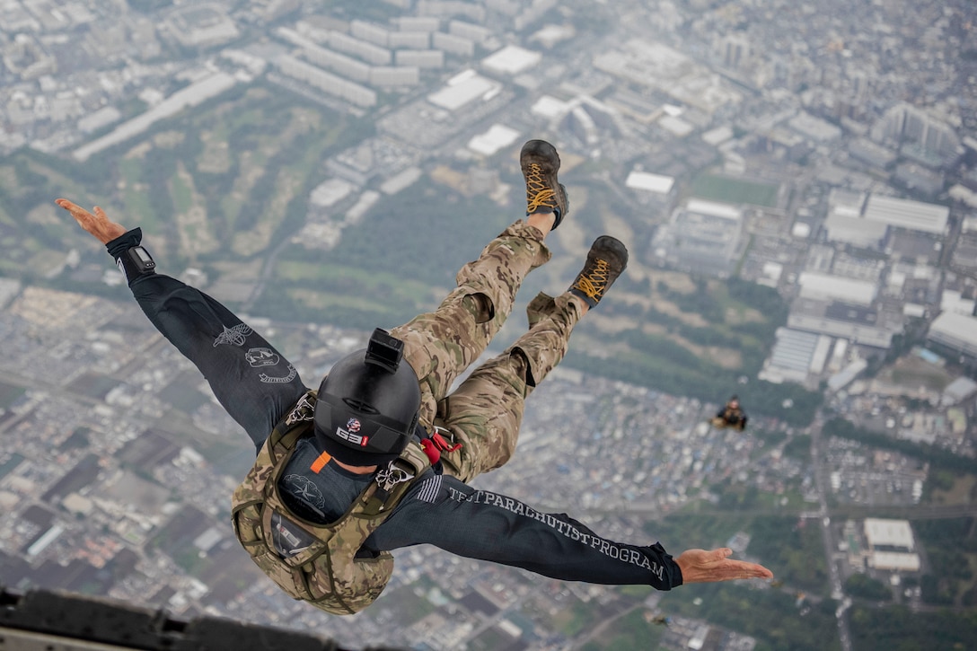 An airman jumps from an aircraft with his legs forward and arms spread wide during a free fall.