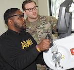 Occupational Therapy Assistant U.S. Army Sgt. Nathan Brunnquell (right) works with Tramel Westbrook on a stationary hand cycle in the Outpatient Occupational Therapy Clinic at Walter Reed.