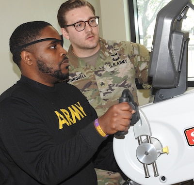 Occupational Therapy Assistant U.S. Army Sgt. Nathan Brunnquell (right) works with Tramel Westbrook on a stationary hand cycle in the Outpatient Occupational Therapy Clinic at Walter Reed.