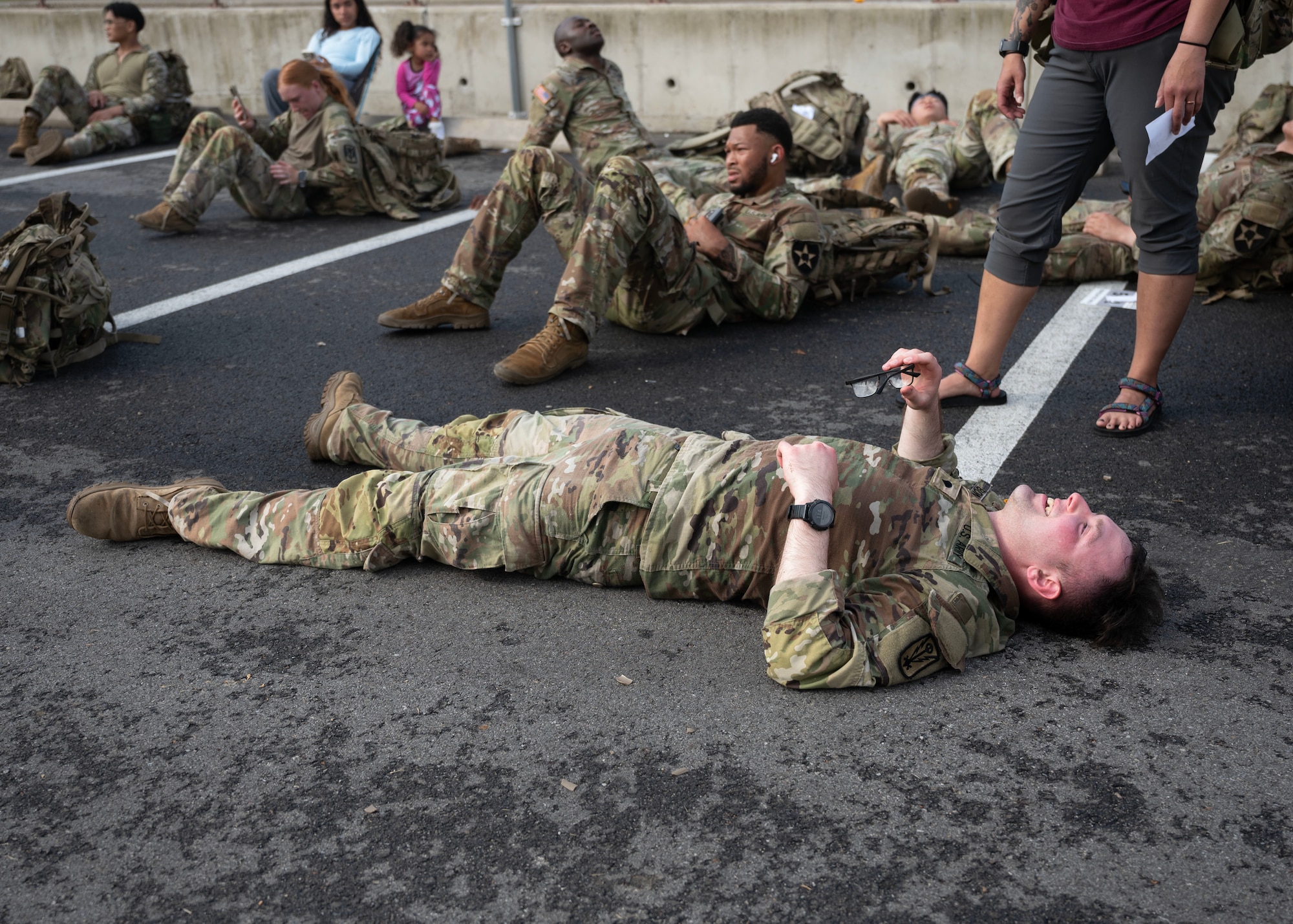 Participants of the Four Chaplain Memorial Run and Ruck rest after finishing the Norwegian Foot March at Osan Air Base, Republic of Korea, May 17, 2025. The NFM is a long-standing military event that challenges participants to march 18.6 miles while carrying a minimum of 25 pounds, completing the ruck within the time set for their age group. (U.S. Air Force photo by Senior Airman Sarah Williams)