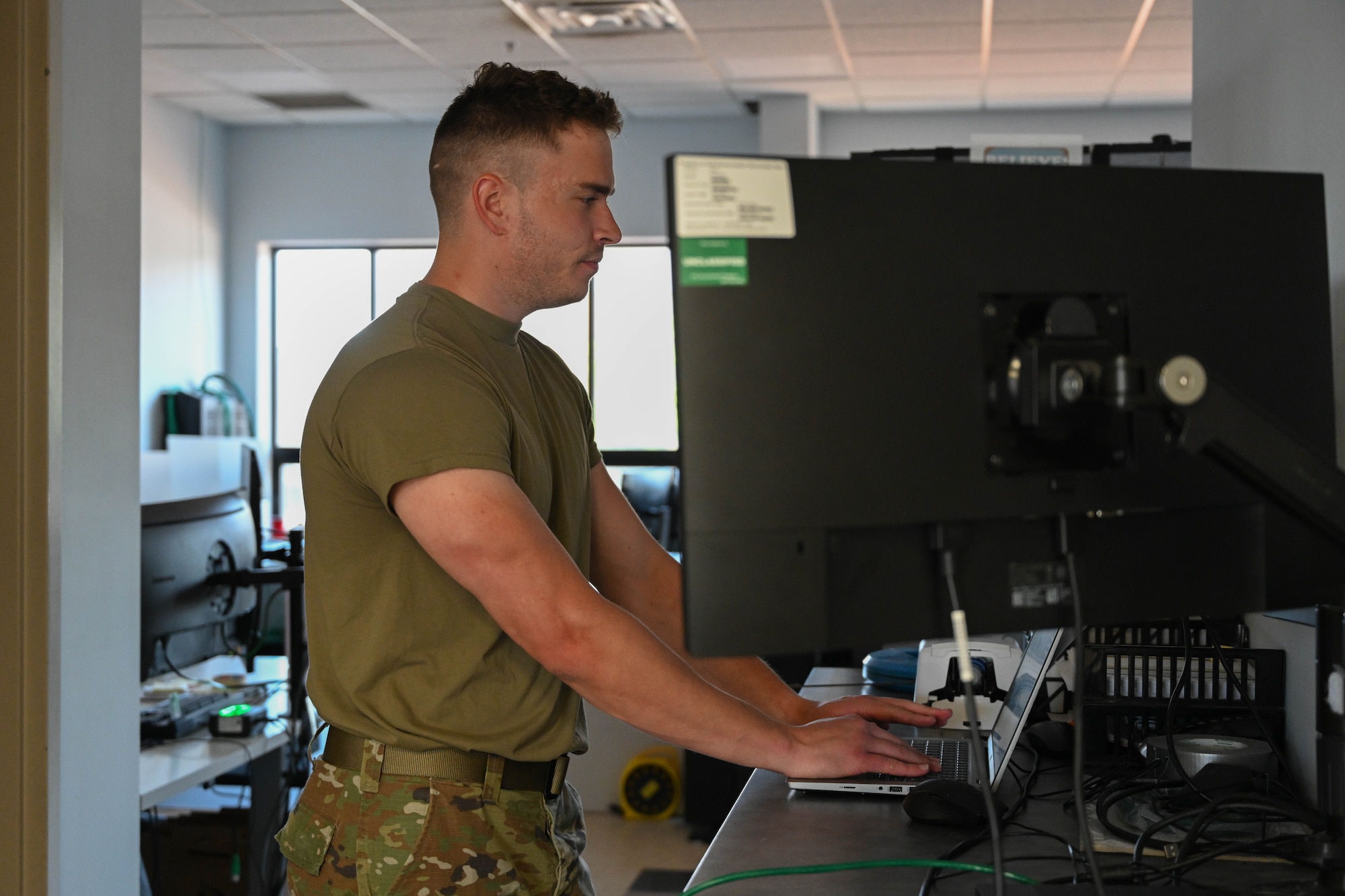 An Airman stands in front of a computer.