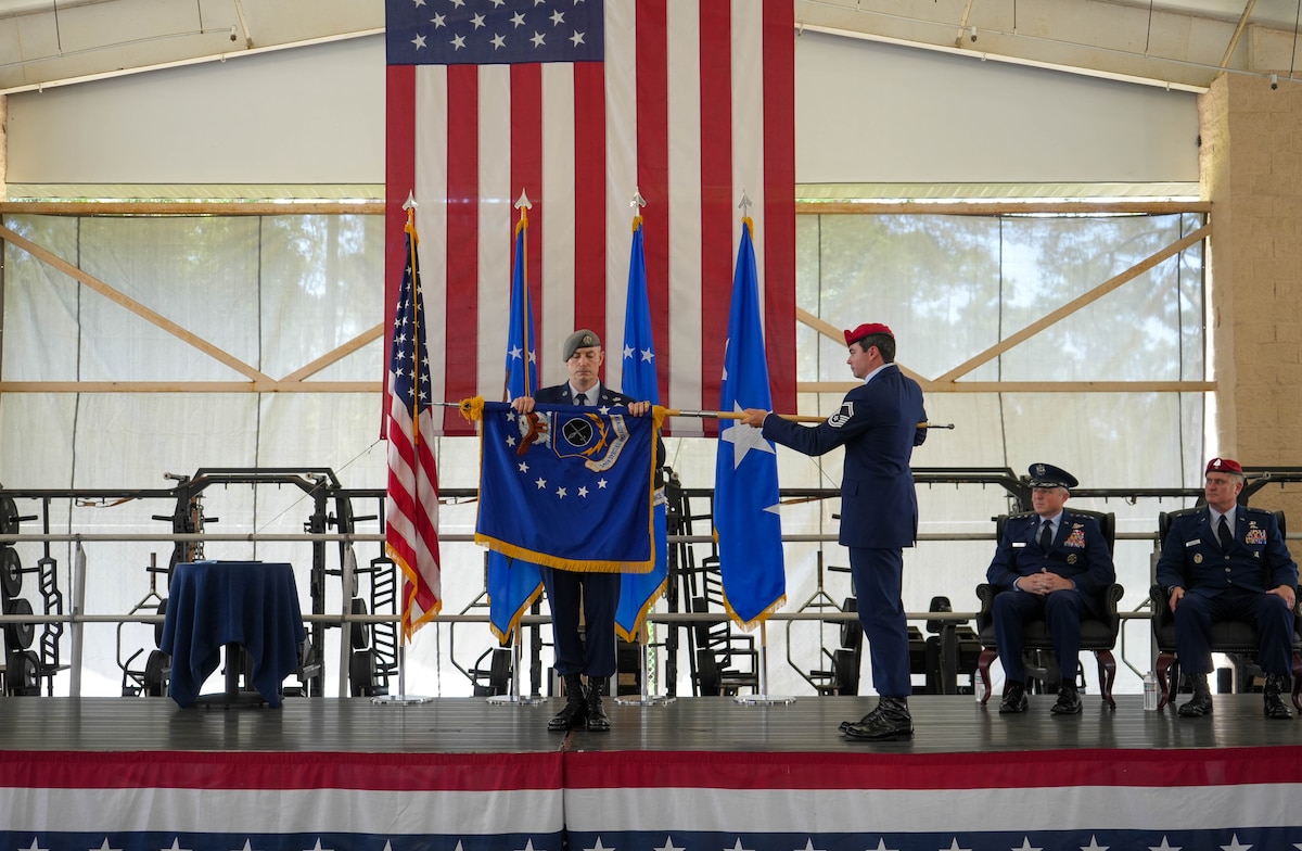 U.S. Air Force Command Chief Master Sgt. Stephen Cox, 24th Special Operations Wing, left, and Senior Master Sgt. Rob Henry, right, Air Force Special Operations Command Special Warfare Division, furl the 24 SOW flag at the 24 SOW flag furling ceremony May 16, 2025, at Hurlburt Field, Fla.
