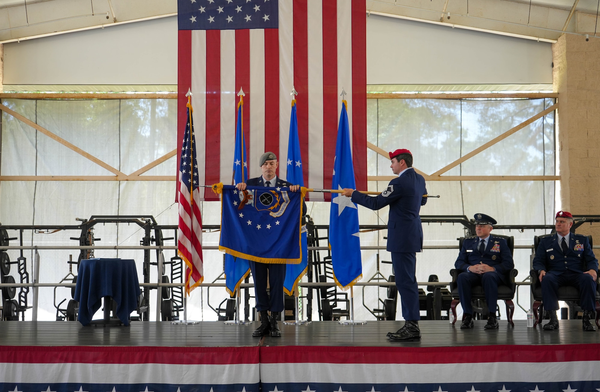U.S. Air Force Command Chief Master Sgt. Stephen Cox, 24th Special Operations Wing, left, and Senior Master Sgt. Rob Henry, right, Air Force Special Operations Command Special Warfare Division, furl the 24 SOW flag at the 24 SOW flag furling ceremony May 16, 2025, at Hurlburt Field, Fla.