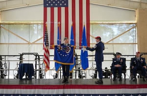 U.S. Air Force Command Chief Master Sgt. Stephen Cox, 24th Special Operations Wing, left, and Senior Master Sgt. Rob Henry, right, Air Force Special Operations Command Special Warfare Division, furl the 24 SOW flag at the 24 SOW flag furling ceremony May 16, 2025, at Hurlburt Field, Fla.