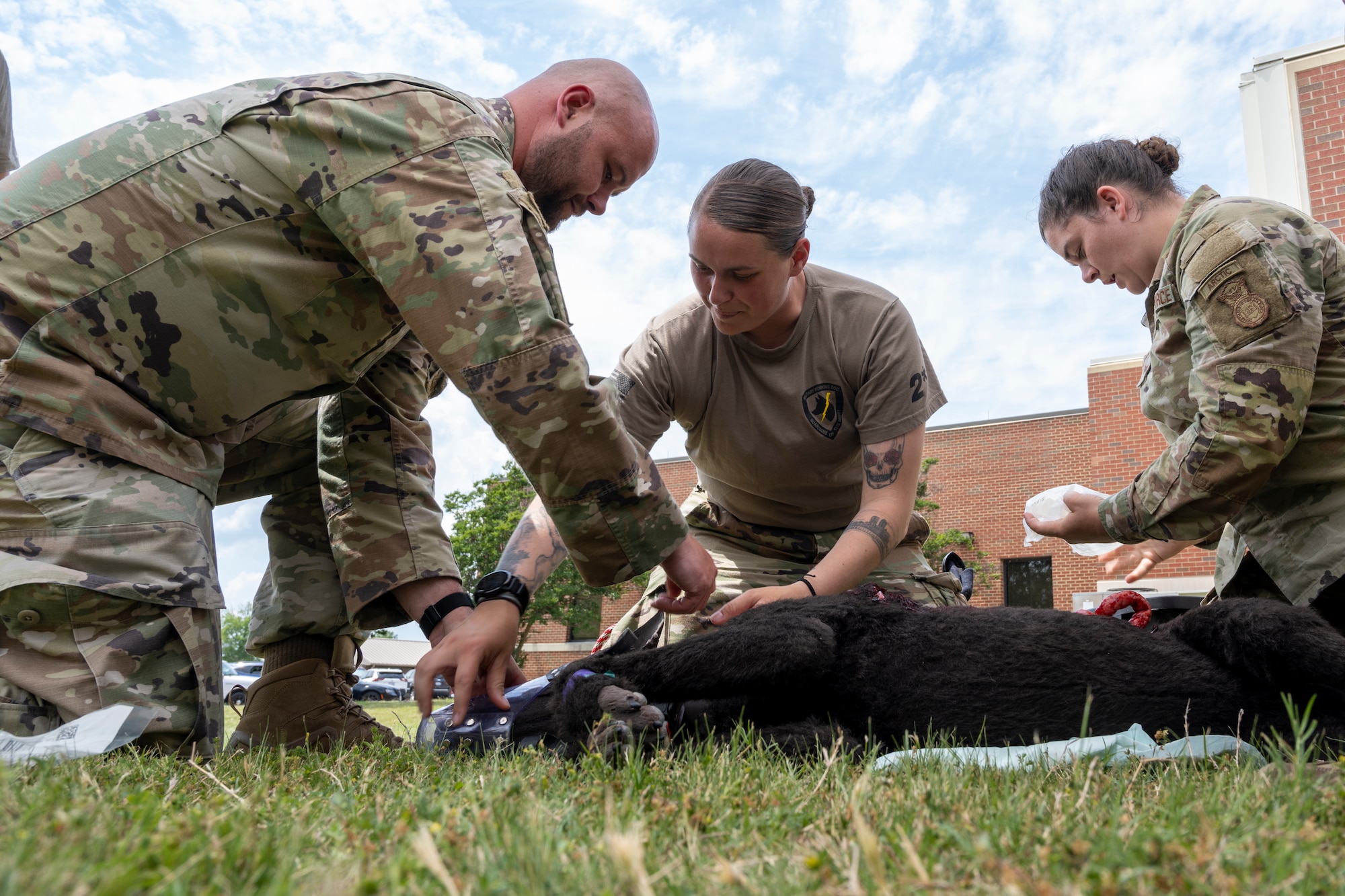 Three Airmen crouch over a diesel K-9 simulator.