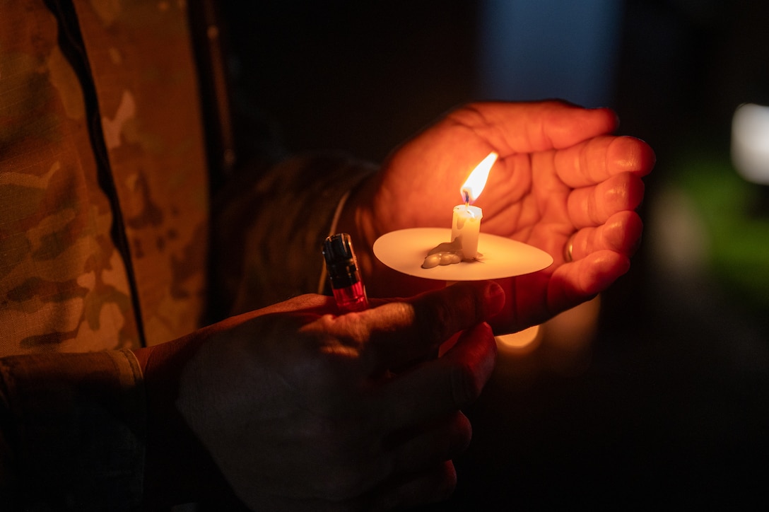 Airman holds a burning candle. (U.S. Air Force photo by Airman 1st Class Skylar Ellis)
