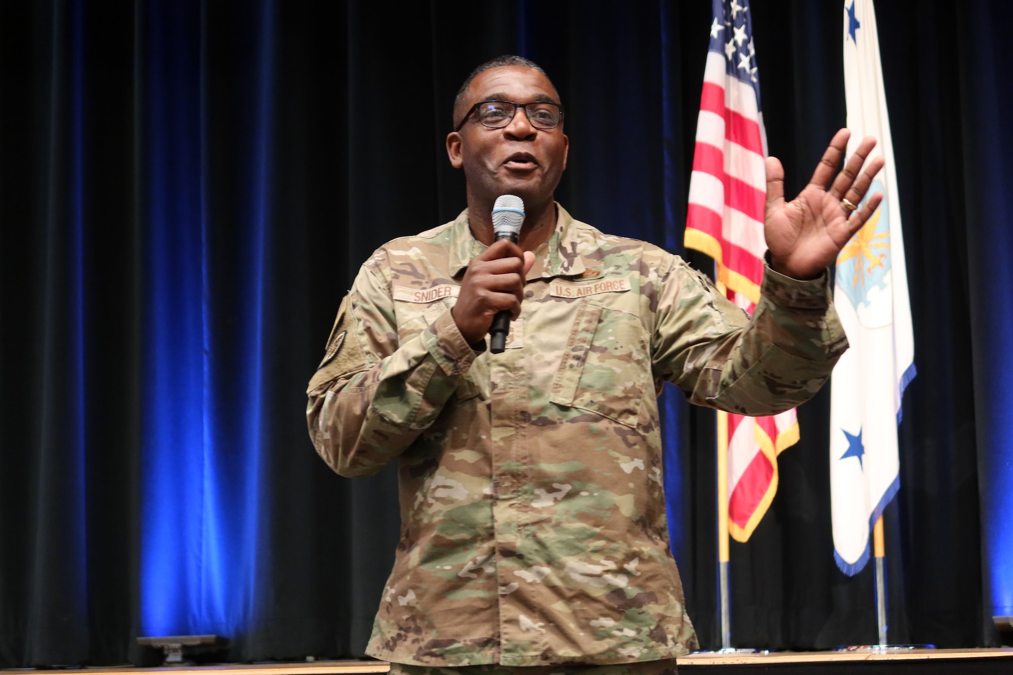 Chief Master Sgt. Wendell Snider holds microphone while sharing story with staff during the quarterly All Call