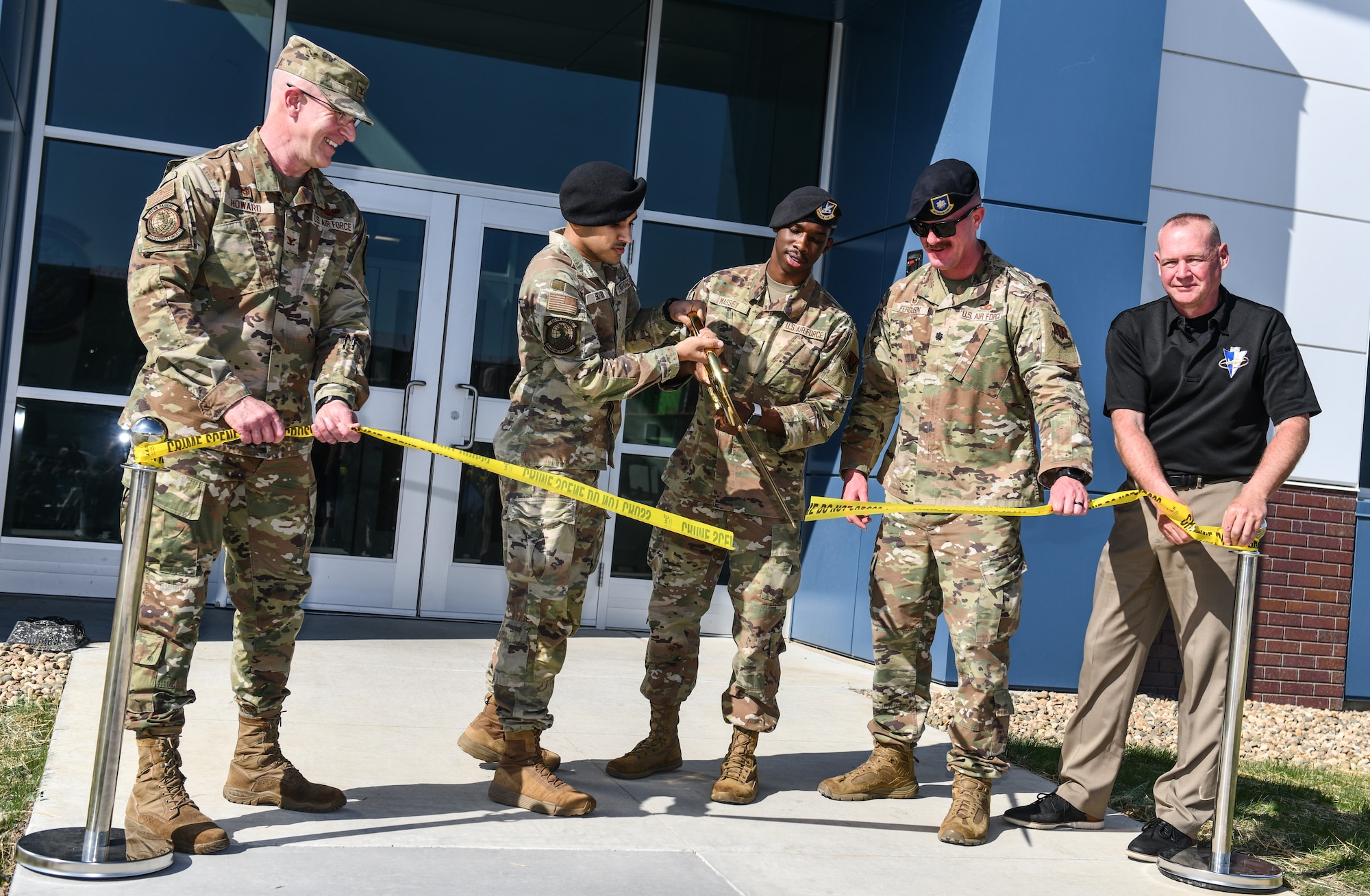 Airman Abeer Siddiqi and Airman 1st Class Shamarion Massey, 55th Security Forces Squadron, cut the ribbon held by Col. Mark Howard, 55th Wing commander, Lt. Col. Andrew Ferguson, 55th SFS commander, and Bellevue Police Chief Ken Clary during the opening of the new SFS campus on Offutt Air Force Base, May 12. (U.S. Air Force photo by Chad Watkins)
