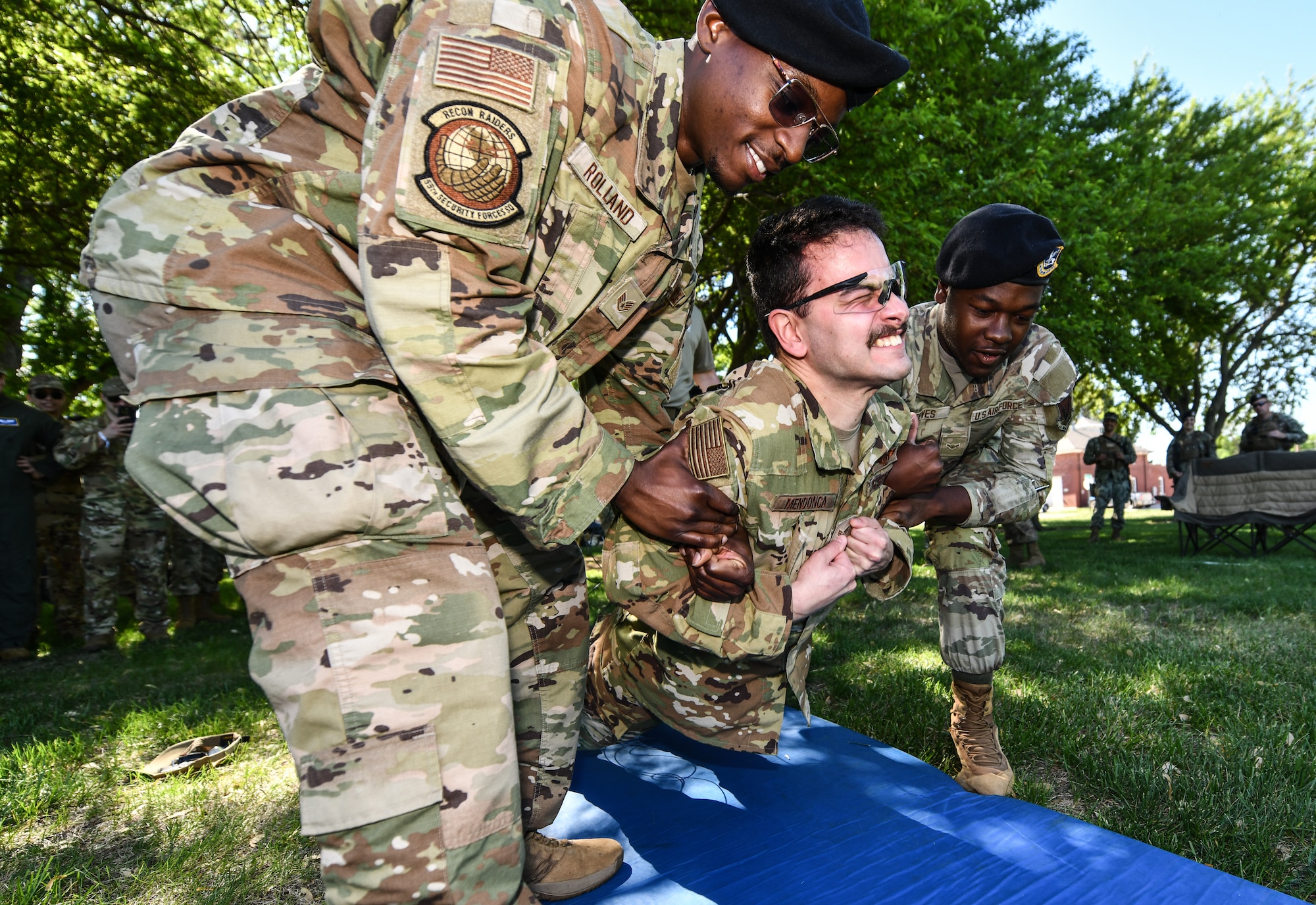 Senior Airman Antonio Menonca, 1st Airborne Command and Control Squadron, is lowered to the ground by Staff Sgt. QuinJuante Rolland, 55th Security Forces Squadron, and Airman Deshawn Reeves, 55th SFS, during a taser demonstration on Offutt Air Force Base, May 13. The 55th SFS conducted taser displays as part of National Police Week festivities. (U.S. Air Force photo by Chad Watkins)