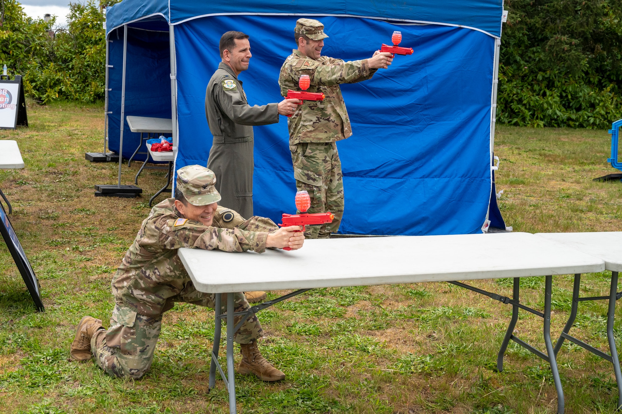 U.S. Army Col. Kent Park, Joint Base Lewis-McChord installation commander, left, U.S. Air Force Col. Sergio Anaya, 62d Airlift Wing commander, center, and U.S. Air Force Col. Brandon Sokora, 627th Air Base Group commander, try out the orbeez gel shooter, one of the many Armed Forces Day games for kids at JBLM Washington, May 16, 2025.