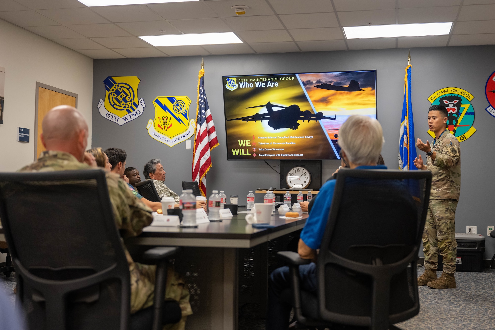 A U.S. Air Force Airmen briefs civilians who are honorary commanders about their upcoming tour of the squadron.