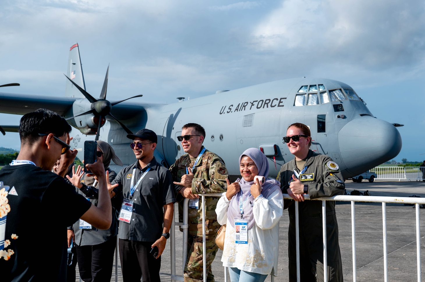 U.S. Air Force Master Sgt. Chaz Burrows, 374th Aircraft Maintenance Squadron programs flight chief, and Tech. Sgt. Kaylynn Staba, 36th Airlift Squadron instructor loadmaster, pose for a photo with attendees at the Langkawi International Maritime and Aerospace Exhibition 2025 in Langkawi, Malaysia, May 20, 2025. The 36 Airlift Squadron maintains mission-ready C-130J aircrew to conduct a wide variety of mission sets; including theater airlift, special operations, and humanitarian aid throughout the Indo-Pacific. (U.S. Air Force photo by Senior Airman Alexzandra Gracey)
