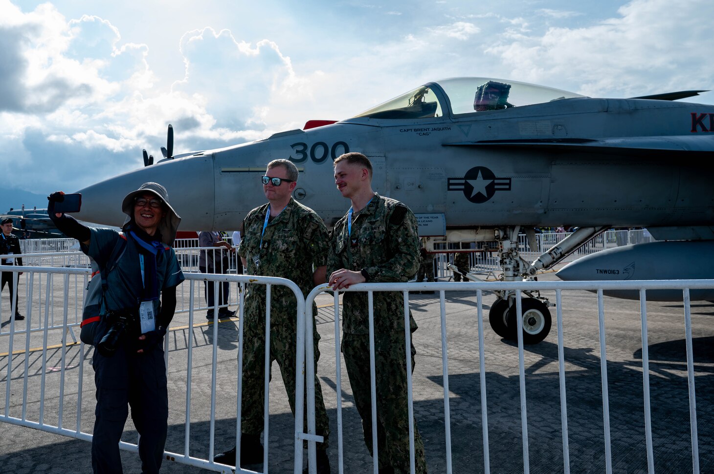 Senior Chief Aviation Electrician's Mate Richard Tretsven, left, and Aviation Electrician's Mate Second Class Marcus Cox pose for a photo in front of an F/A-18E Super Hornet from the “Kestrels” of Strike Fighter Squadron (VFA) 137 with an attendee at the Langkawi International Maritime and Aerospace Exhibition 2025 in Langkawi, Malaysia, May 20, 2025. LIMA 25 is a biennial event that brings together industry stakeholders and government and military leaders from more than a dozen nations for a five-day event dedicated to the maritime and aerospace sectors for defense, civil and commercial applications. (U.S. Air Force photo by Senior Airman Alexzandra Gracey)