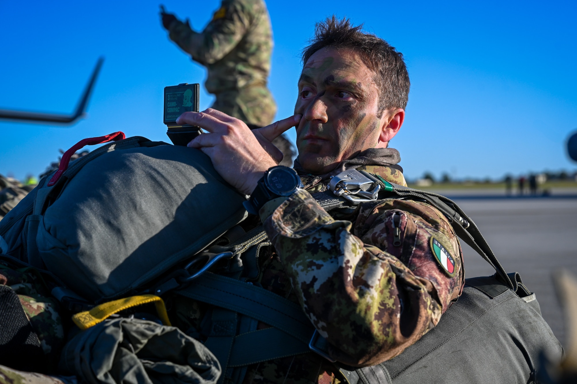 An Italian paratrooper applies face paint prior to boarding a C-17 Globemaster III during Swift Response 25 at Spangdahlem Air Base, Germany, May 16, 2025.