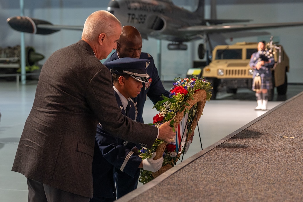 Three men place a wreath onto an easel