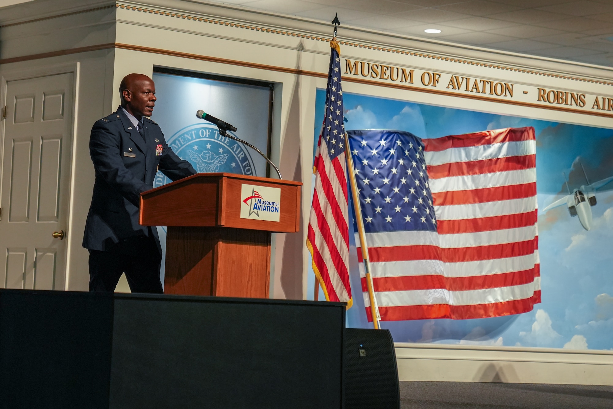 Man in military uniform speaking behind a podium