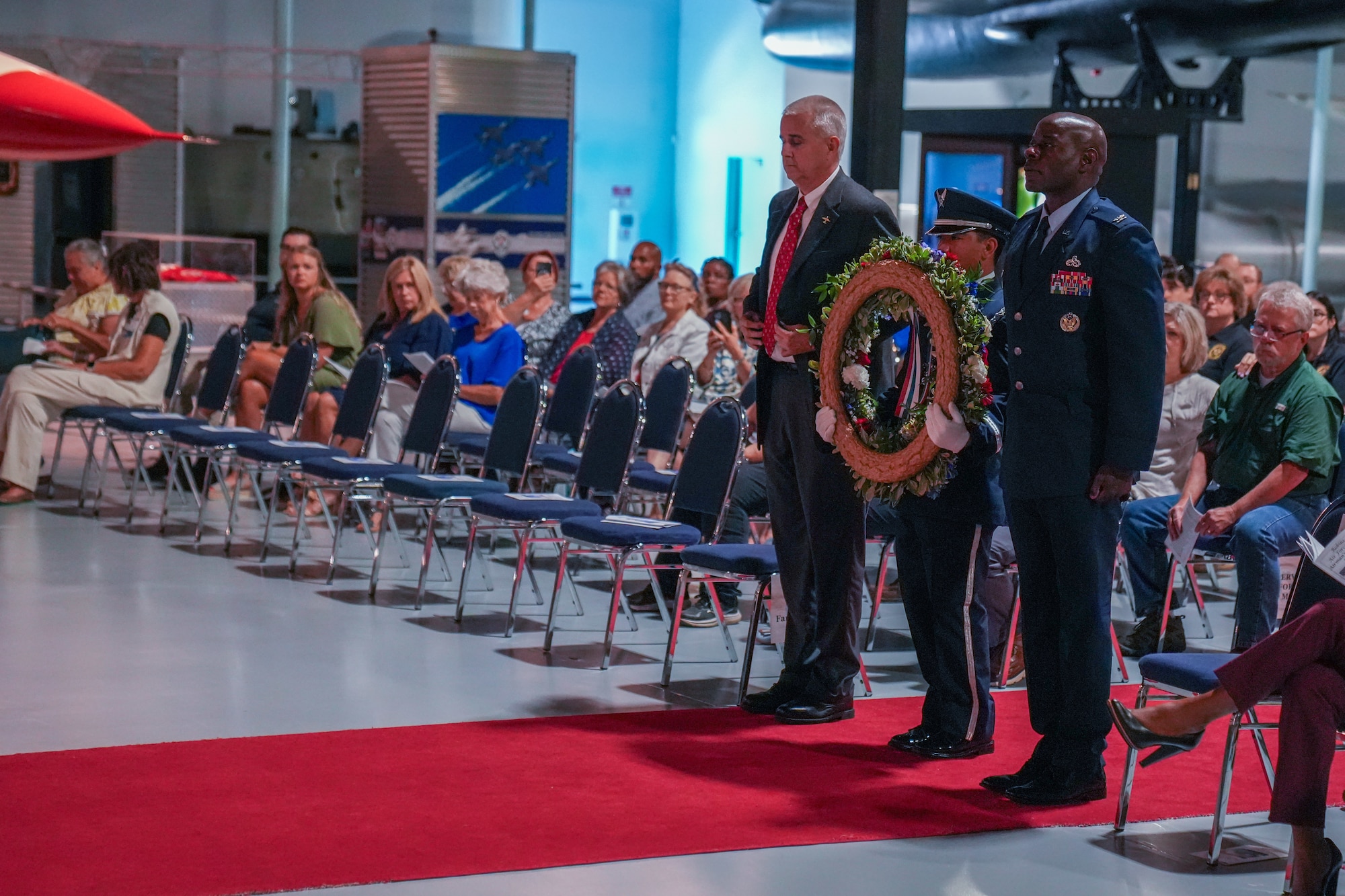 Three men standing still while middle person is holding a wreath