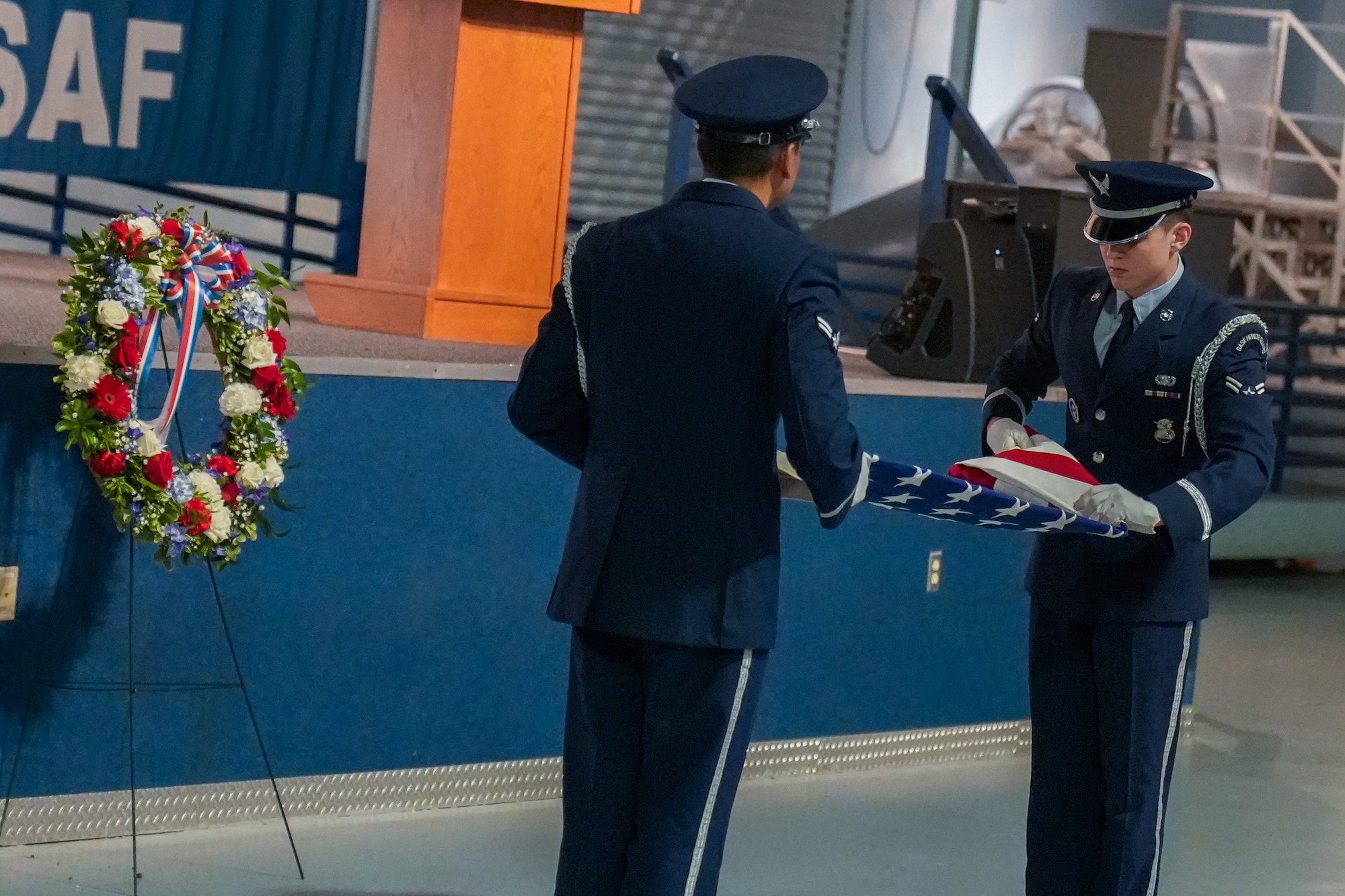 Two men in military uniform folding an American flag